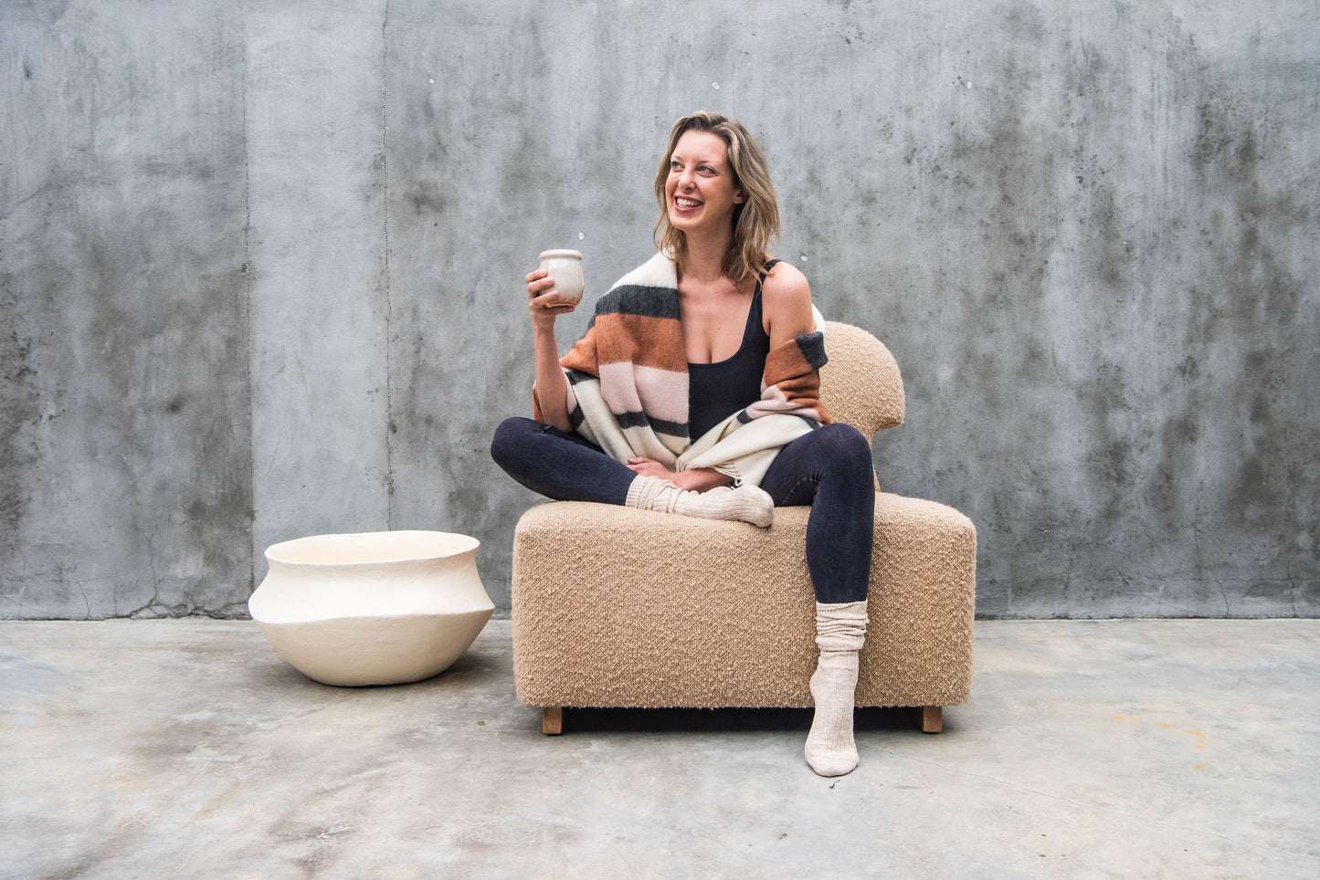 Women drinking tea and appearing happy while sitting in a relaxed position on Dune-colored bouclé Meditation Chair by Rue and Williams Home. Modern design with no arms and a curved back, perfect for enhancing mindfulness practices and adding tranquility to any space.