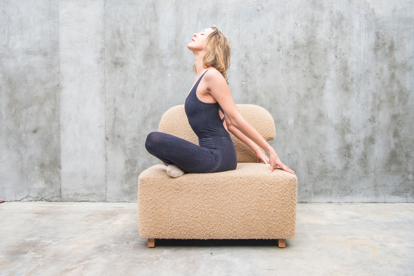 Women posing on Dune-colored bouclé Meditation Chair by Rue and Williams Home. Modern design with no arms and a curved back, perfect for enhancing mindfulness practices and adding tranquility to any space.